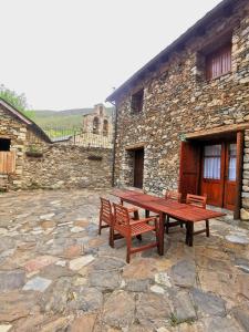 CardetTríplex con patio y BBQ en La Vall de Boí的石头建筑前的木餐桌