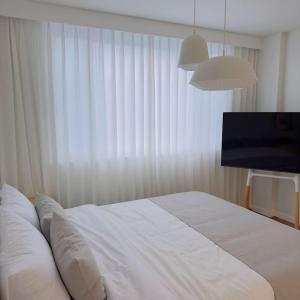 巨济Stay Saeroc的卧室配有白色的床和电视。