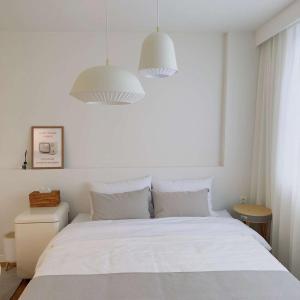 巨济Stay Saeroc的一间卧室配有一张白色床和两盏吊灯