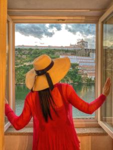 波尔图Red House By The River的一位戴帽子的女人,看着窗外