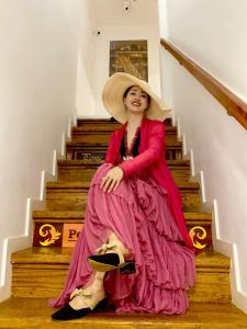 波尔图Red House By The River的坐在楼梯上的穿着粉红色衣服的女人