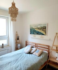詹塔尔Apartament Morze Sztuki, Jantar的一间卧室配有一张带枕头的床和吊灯。