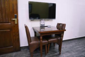 拉合尔Hayyat Luxury Suites的一张桌子、两把椅子和墙上的电视