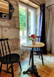 Parçay-les-PinsLe Clos des Roses的窗户间里的一张桌子和两把椅子
