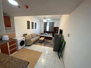 阿吉曼Apartment in Ajman,Studio flat的厨房以及带沙发和微波炉的客厅。