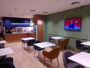 马德里HelloSky Air Rooms Madrid的一间带桌椅的餐厅以及墙上的电视
