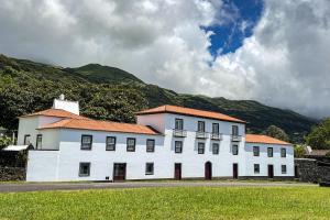 Fajã de Santo AmaroQuinta dos Mistérios- Turismo de Habitação的一座白色的大建筑,背景是一座山