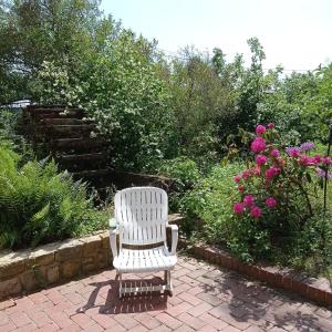 RentyLe gîte de l'AA的花卉砖砌的庭院里,摆放着白色椅子