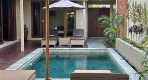 塞隆贝拉纳克Pandan Villas的一座房子旁带遮阳伞的游泳池