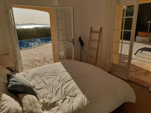 滨海卡瓦莱尔4-Star Private Villa with Heated Pool and Panoramic Sea View at Gulf de Saint Tropez的一间卧室设有一张床和一个滑动玻璃门