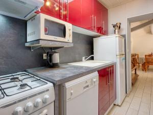Gaillan-en-MédocHoliday Home Nola - GEM100 by Interhome的厨房配有红色橱柜和白色炉灶烤箱