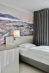 奥斯陆Super Stay Hotel, Oslo的酒店客房设有一张床,墙上挂有绘画作品