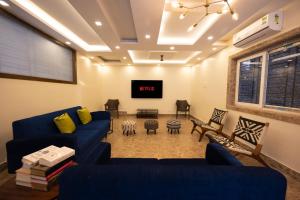 加尔各答Lakeside Suites的客厅配有蓝色的沙发和平面电视。