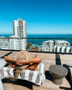 开普敦Home Suite Hotels Station House的坐在俯瞰大海的阳台毛巾上的女人