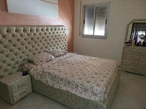Al HachlafAppartement near airport ouled tayeb的一间卧室配有一张大床和软垫床头板