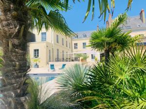 拉弗雷切Les Chambres de La Varenne的一座带游泳池和棕榈树的大房子
