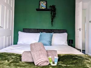 西部德比No 51 - Spacious 3 Bed Home - Free Parking - Wi-Fi - Contractors的绿色卧室,配有带毛巾的床