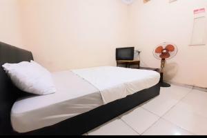 北干巴鲁SPOT ON 92599 Pondok Anggrek Syariah的一间卧室配有一张床,并在一间客房内配有电视。