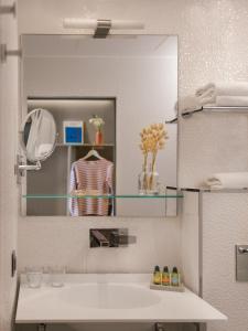 巴黎Legend Hôtel Paris的浴室设有镜子和白色水槽