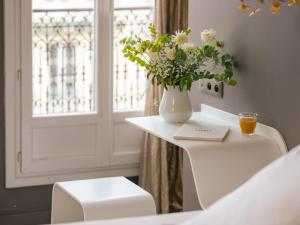 巴黎Legend Hôtel Paris的花瓶坐在白色的桌子上,有窗