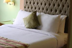 开罗开罗桑塔纳酒店的一张带白色枕头的床和一个灰色床头板
