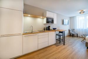 林道bodenseezeit Apartmenthotel Garni的一间厨房,内设白色橱柜和一张桌子