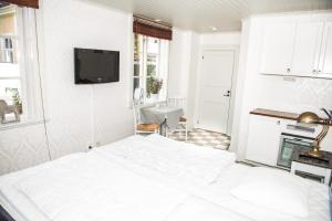 南雪平Johannas GuestHouse的白色卧室设有一张床和墙上的电视