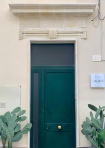 莱切HABITARE Lecce & Salento的白色建筑中绿门,有植物
