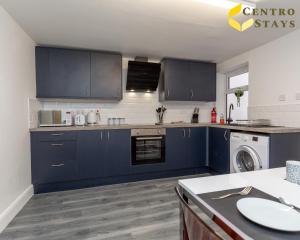 北安普敦Relocation Families Contractors FREE PARKING的厨房配有蓝色橱柜、洗衣机和烘干机