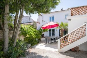 雷岛林滩Maison Les Burons的房屋设有带红色遮阳伞的庭院