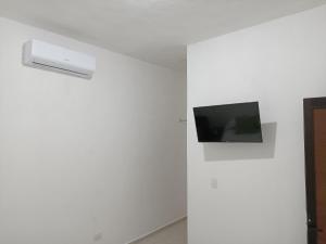 坎昆Casa Tauch的客房内白色墙壁上的平面电视