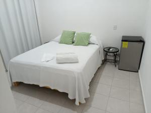 坎昆Casa Tauch的一张白色的床,上面有绿色枕头