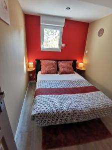 Longues-sur-MerLa chaumière的一间卧室配有一张红色墙壁的床