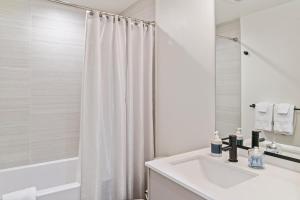 西雅图Modern apartment near light rail的白色的浴室设有水槽和淋浴。