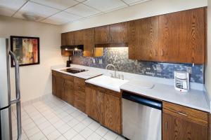 罗切斯特卡勒旅馆及套房酒店的厨房配有木制橱柜、水槽和洗碗机。