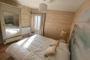 滨海吕克Charming little house with exposed stonework的一间卧室配有一张大床和镜子