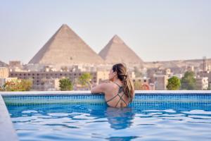 开罗New Pyramid Front Hotel的身后有金字塔的游泳池中的女性