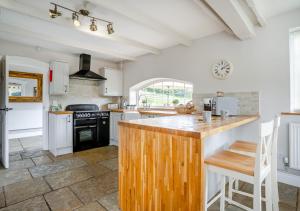 TrehafodHafod Ganol Farm的厨房配有白色橱柜和木制台面