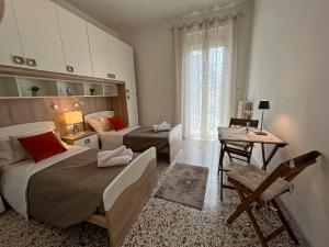 圣贝内代托-德尔特龙托Appartamento Nautes的一间卧室设有两张床、一张桌子和一个窗口。