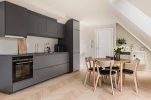 卑尔根Dinbnb Apartments I Mid-City Luxury with Mini Balcony and Smart TV & Sound System的厨房配有黑色橱柜和桌椅