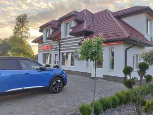 YavorivМотель "КАЛИНА"的停在房子前面的蓝色汽车