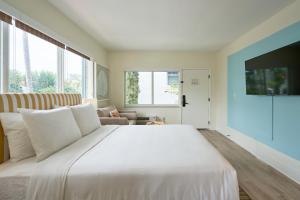 迈阿密海滩Aloha Fridays的卧室配有一张白色的大床和一张沙发。