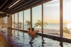 圣玛尔塔祖阿纳海滩度假酒店的坐在游泳池旁的男人和女人