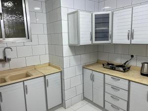 利雅德Hakimdom Hostel的白色的厨房配有白色橱柜和水槽