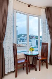 头顿Queen Garden Hotel & Apartment的一间带桌子和两把椅子的用餐室以及窗户。