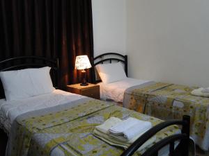 乌姆盖斯( b&b ) Gadara rent room的酒店客房设有两张床和一张带台灯的桌子。