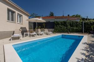 斯普利特Villa KaTess with heated pool的房屋旁的游泳池配有椅子和遮阳伞