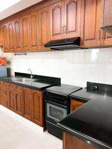 碧瑶Cozy Millenium House的厨房配有木制橱柜和黑炉灶烤箱。