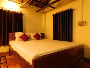 加尔各答Gram Bangla Retreat的一间卧室配有带白色床单和红色枕头的床。