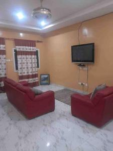 班珠尔Comfy & cozy 2 bedroom apartment, entire unit!的客厅配有2张红色沙发和1台平面电视